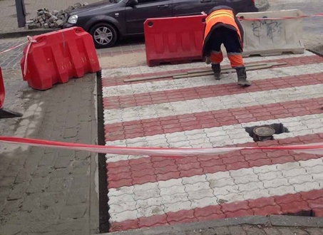 На вул. Ольгинській тривають роботи з влаштування пішохідного переходу з кольорової бруківки червоно-білого кольору